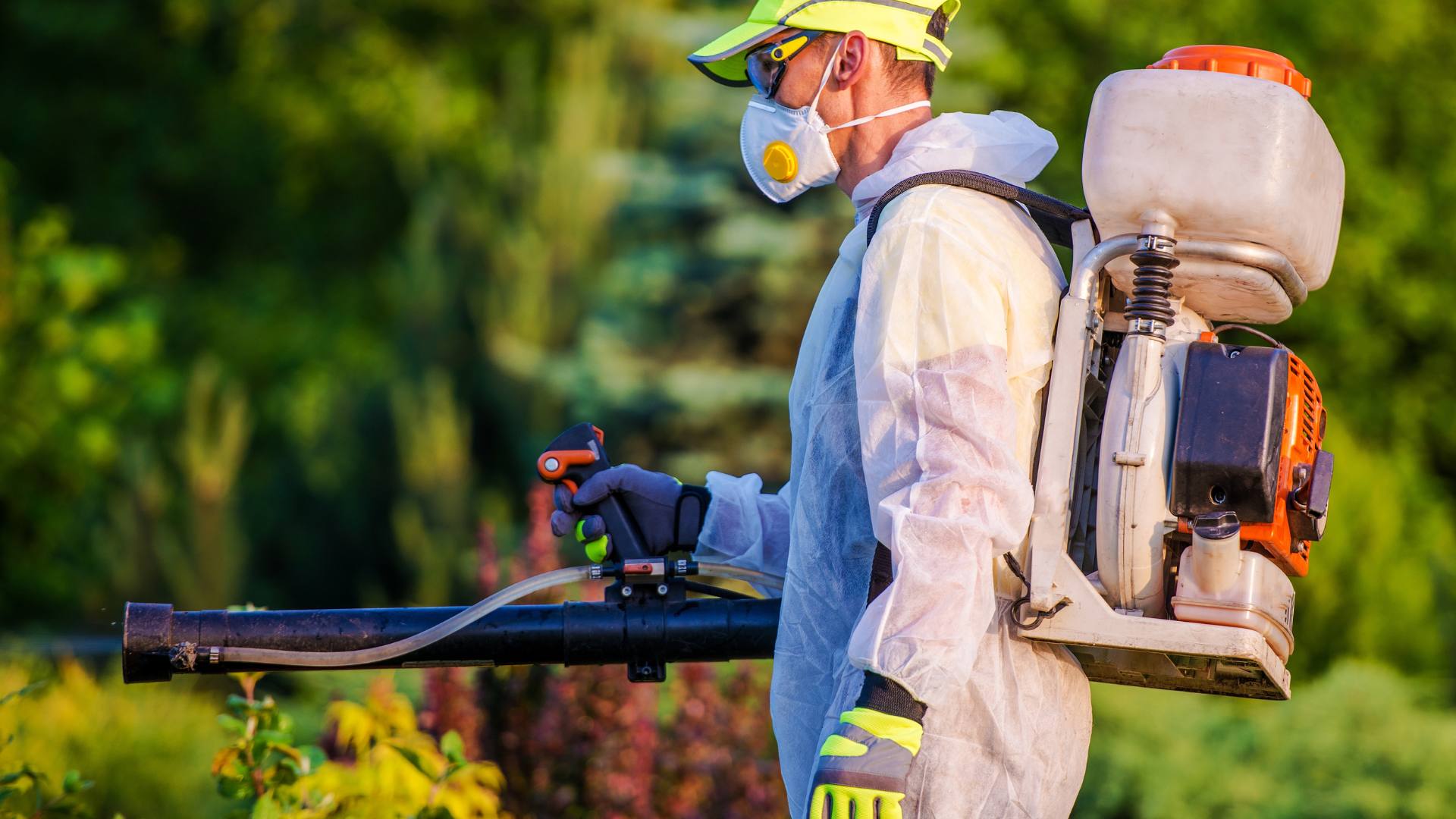 An exterminator handles outdoor spraying as part of pest control services.